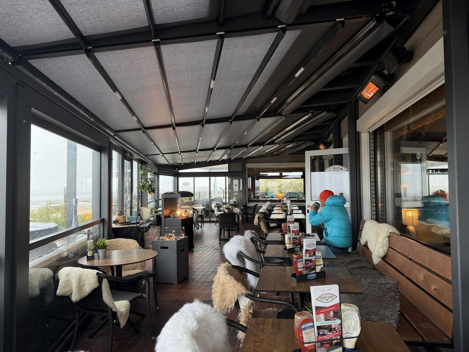 Geschlossene Pergola Silver im Beach Home Cuxhaven. Bei stürmischen Küstenwetter ist das Balkonrestaurant dank der Heizstrahler und den geschlossenen Glaselementen gut nutzbar